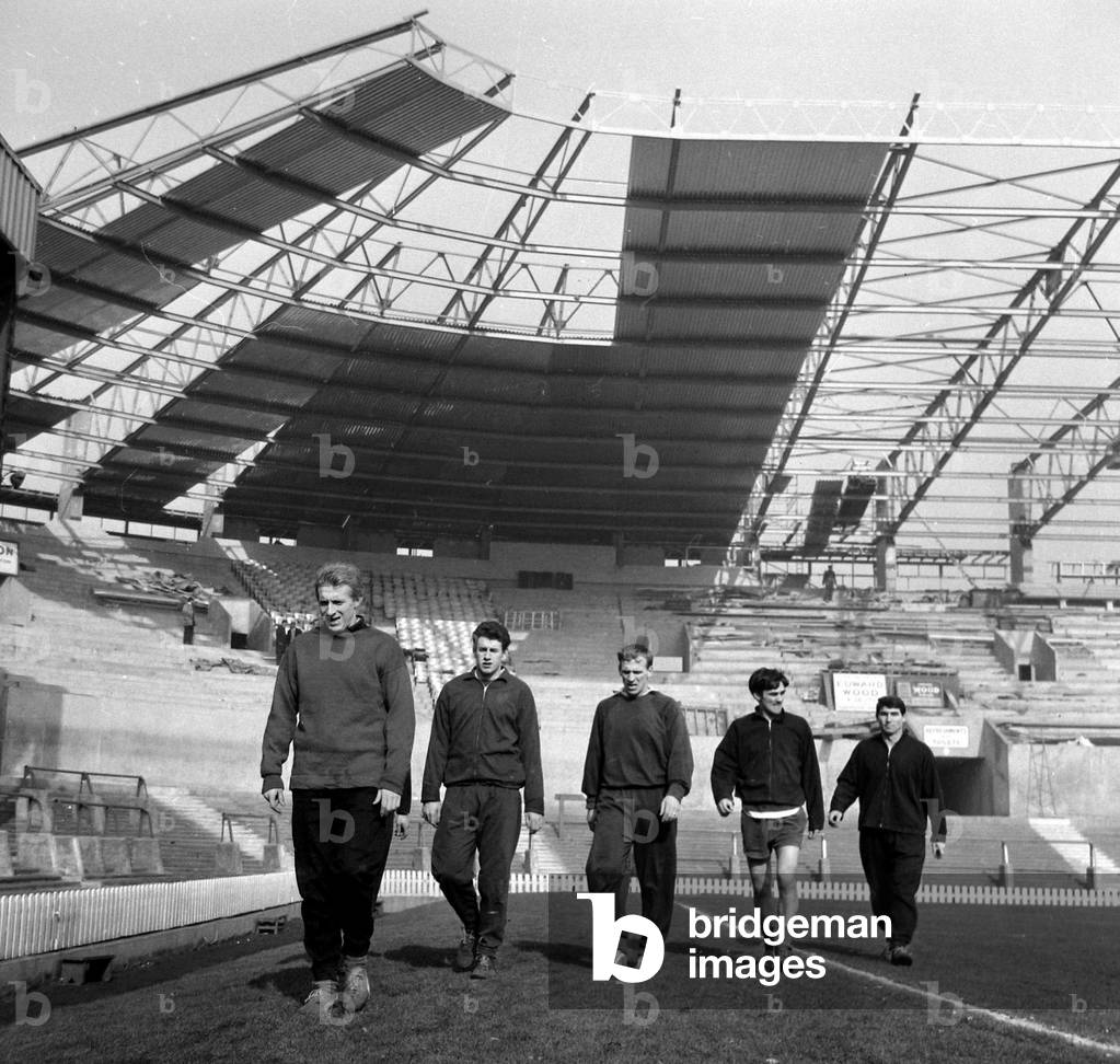 Manchester United Football Players-Players training under the new cantilever stand at Old Trafford. Left to right are Denis Law, Pat Dunne, Paddy Crerand, George Best and Tony Dunne. 10th March 1965 (photo)