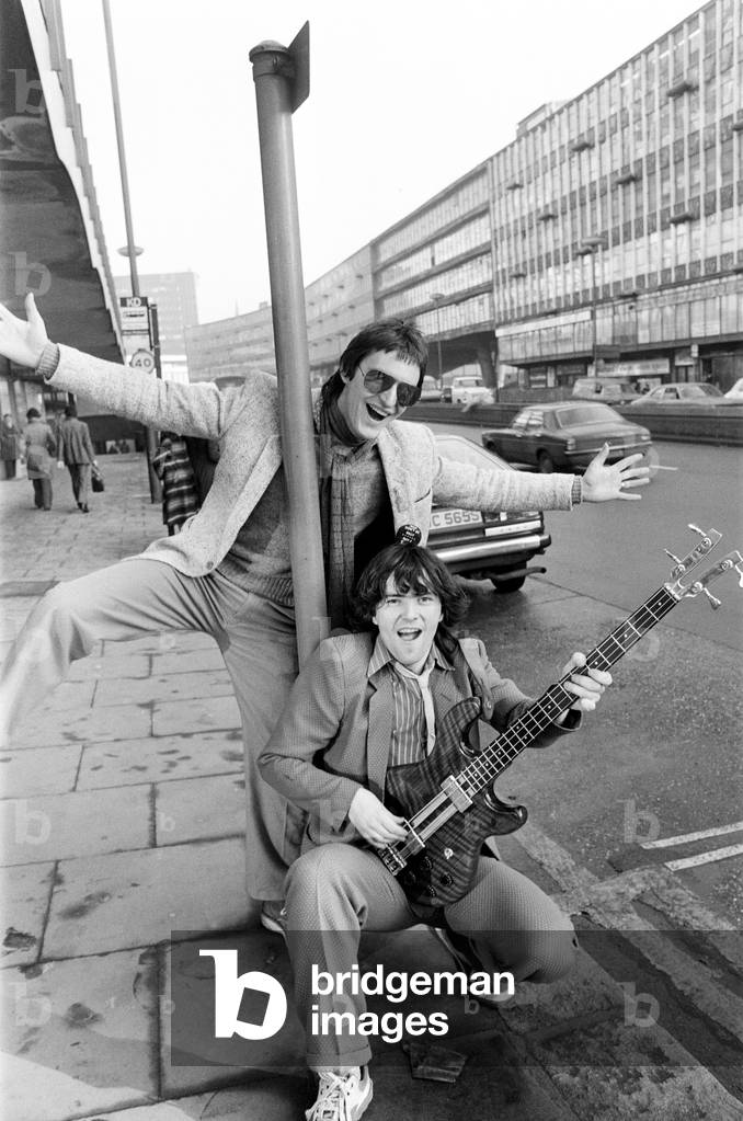 Guitarist Gerry Cott (standing) and bass player Peter Briquette from the Boomtown Rats visited Birmingham to make a trade presentation at a city music shop. 12th January 1979 (b/w photo)