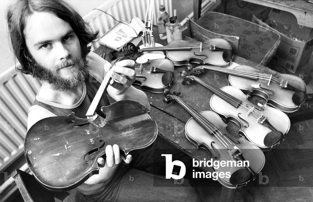Tarquin Bolton at the Sunderland Violin Hospital set up to repair damaged school musical instruments, July 1980 (b/w photo)