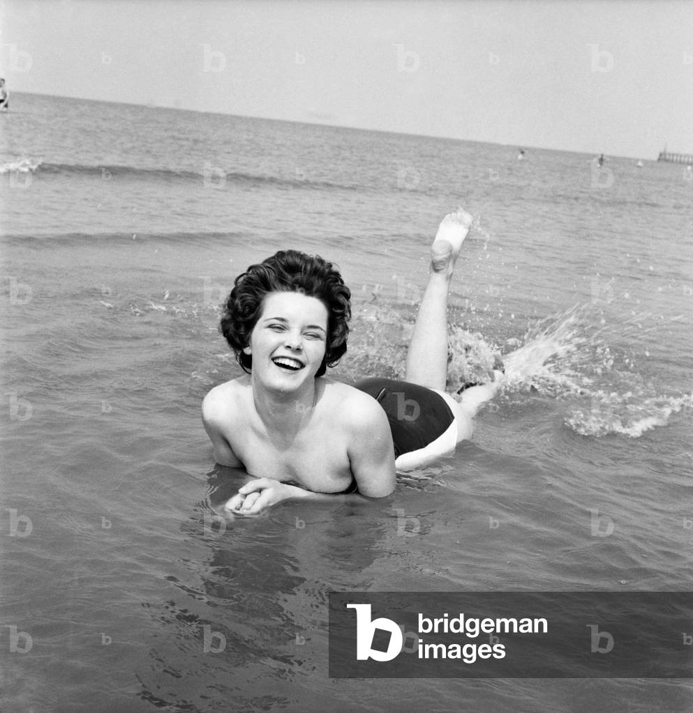 Bank holiday at Blackpool. Beach scenes/crowds/sunbathing. Carole Horrobin, 16, soaks up sun and salt water in the shallows at Blackpool today. She comes from Stoke on Trent. June 1960