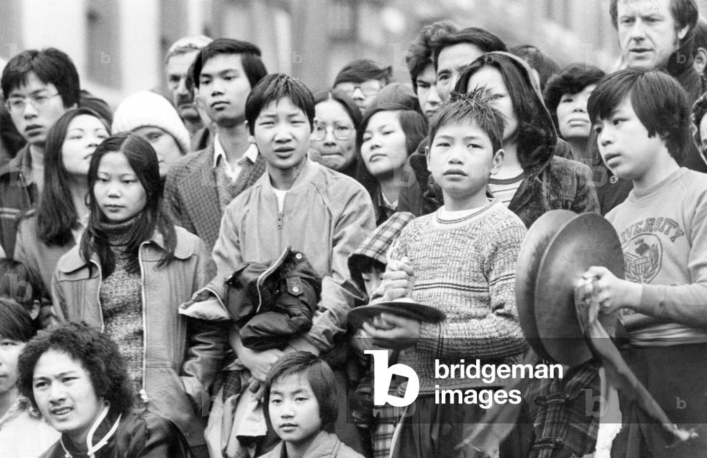 Liverpool's Chinese community ushered in the Year of the Snake with traditional celebrations. Spectators brave the rain to watch the festivities in Chinatown, Liverpool, Merseyside. 18th February 1977 (b/w photo)
