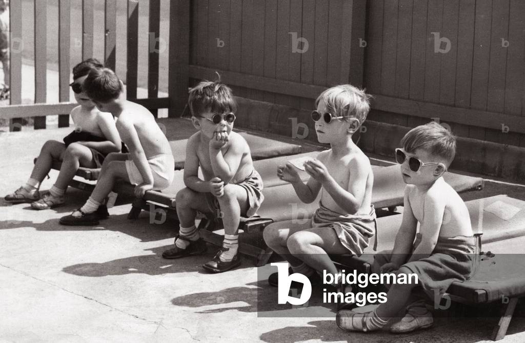On a hot day in Newcastle, children at the New Bridge Street day nursery decided to do a bit of sun bathing complete with sun glasses. They just took their beds outside. August 1952