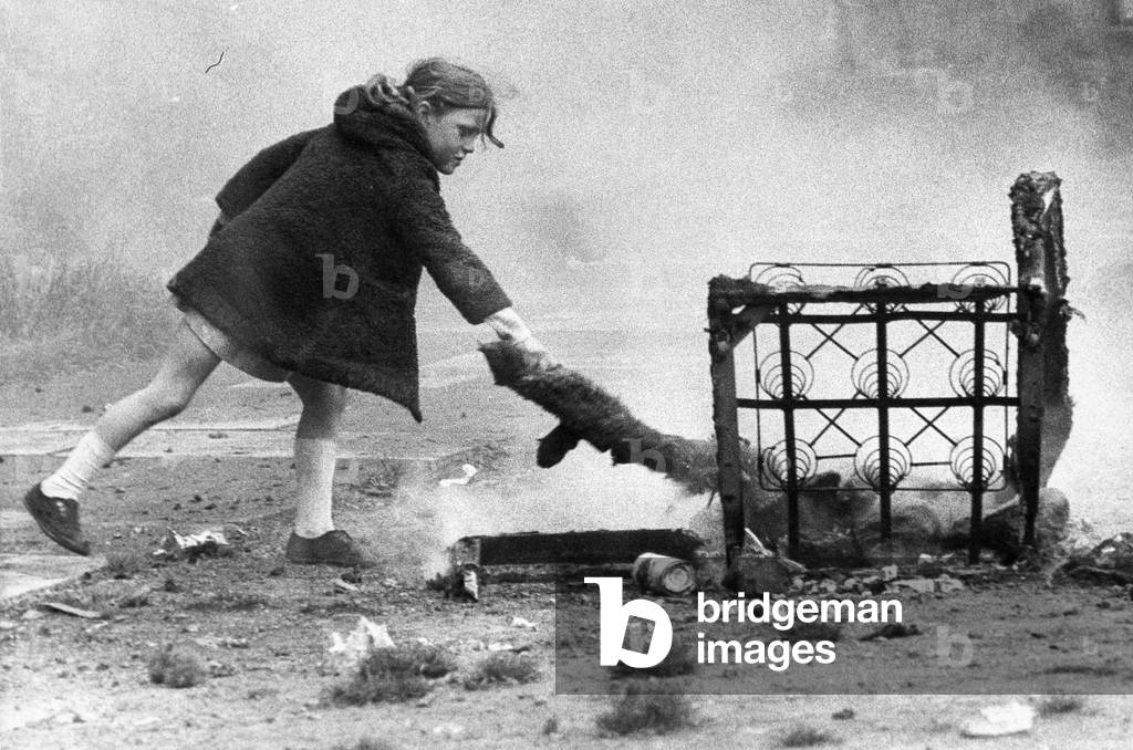 A young girl risks injury playing with fire on wasteland c. November 1970