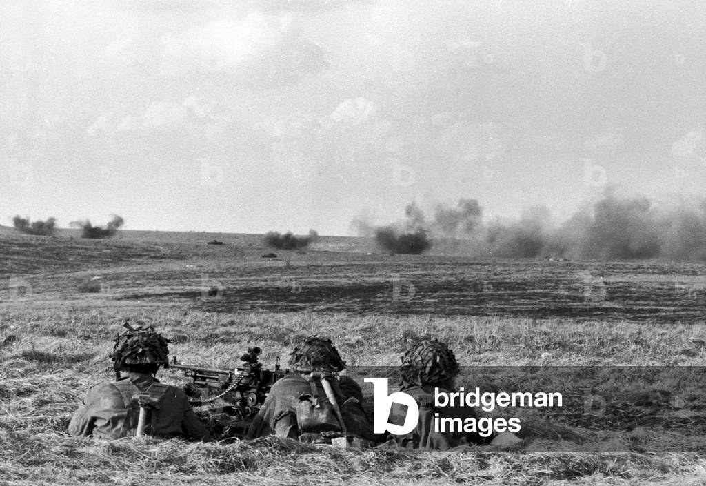 Royal artillery seen here laying down a barrage during an exercise on Salisbury Plain watched be members of the infantry from the comfort of a foxhole. 4th April 1968 (b/w photo)