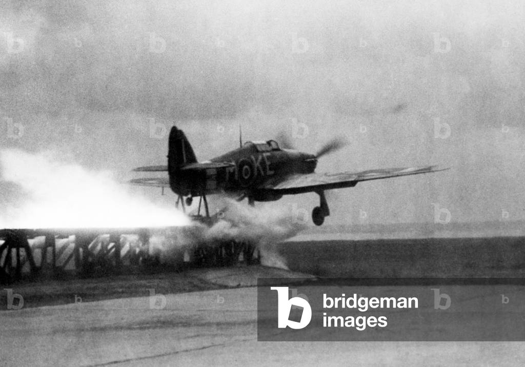 A Royal Air Force Hawker Hurricane is catapulted down a launching ramp on the bow of a merchant ship. These aircraft, used to patrol convoys while at sea, were ditched in the sea when they ran out of fuel and later hoisted back on board the ship. World war Two 1945 (b/w photo)