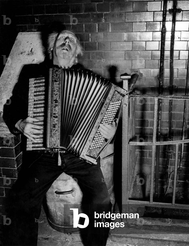 Buskers. Standing all day with an accordian is tiring - so Gus Andrews uses a garbage can for a stool.