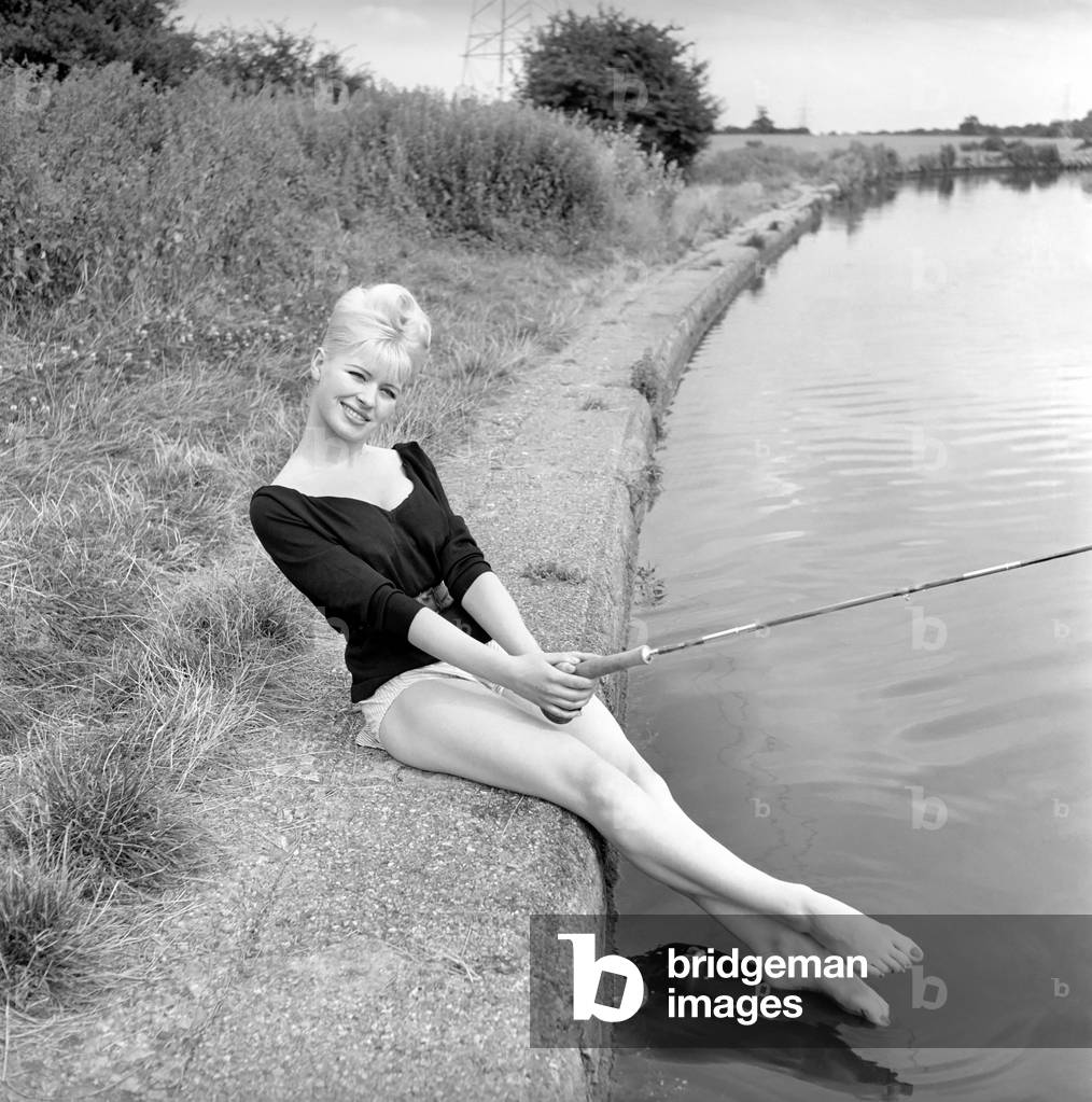 Beachwear Model by the river bank fishing, August 1963 (b/w photo)