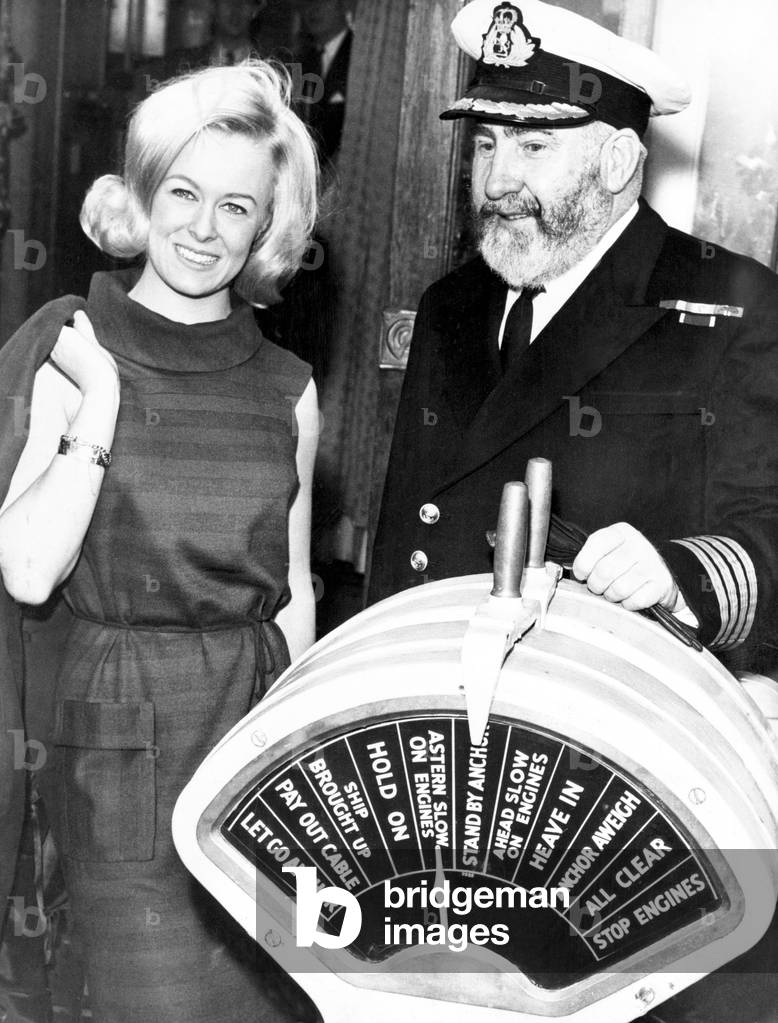 Miss Liverpool, Maureen Martin, with Commodore William E Warwick CBE RD RNR who was the first Master of the QE2 before he retired in 1972. Pictured aboard the Carinthia in Liverpool, Merseyside, 8th December 1966 (b/w photo)
