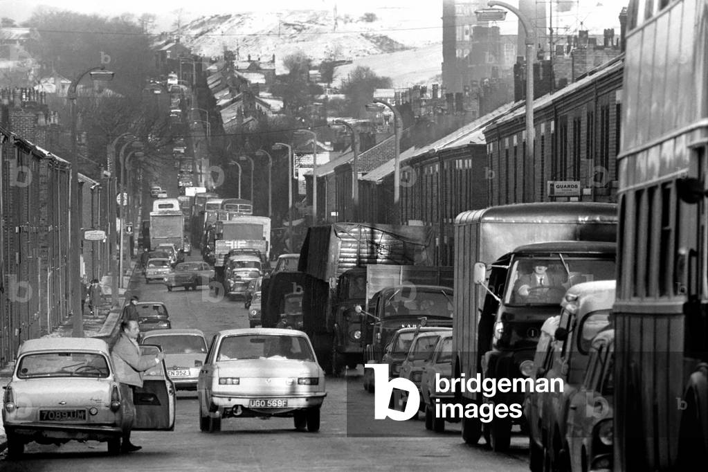 Traffic chaos, around Oldham, as snow, and Ice hit the North. Ice covered road, along the steep slope of Manchester Road, Oldham, as traffic crawls along, 28th November 1969 (b/w photo)