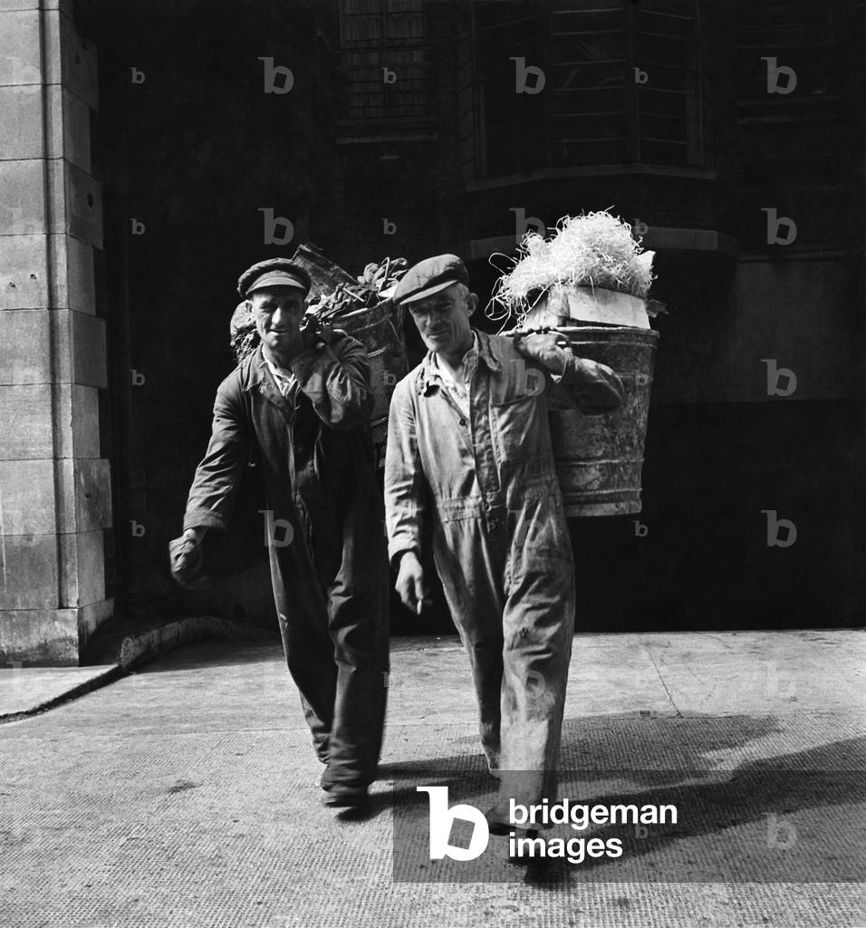 A Cockney earns his living: They've chosen the hard way to collect a weekly pay packet - two dustmen leave a block of London flats by the back way. August 1947