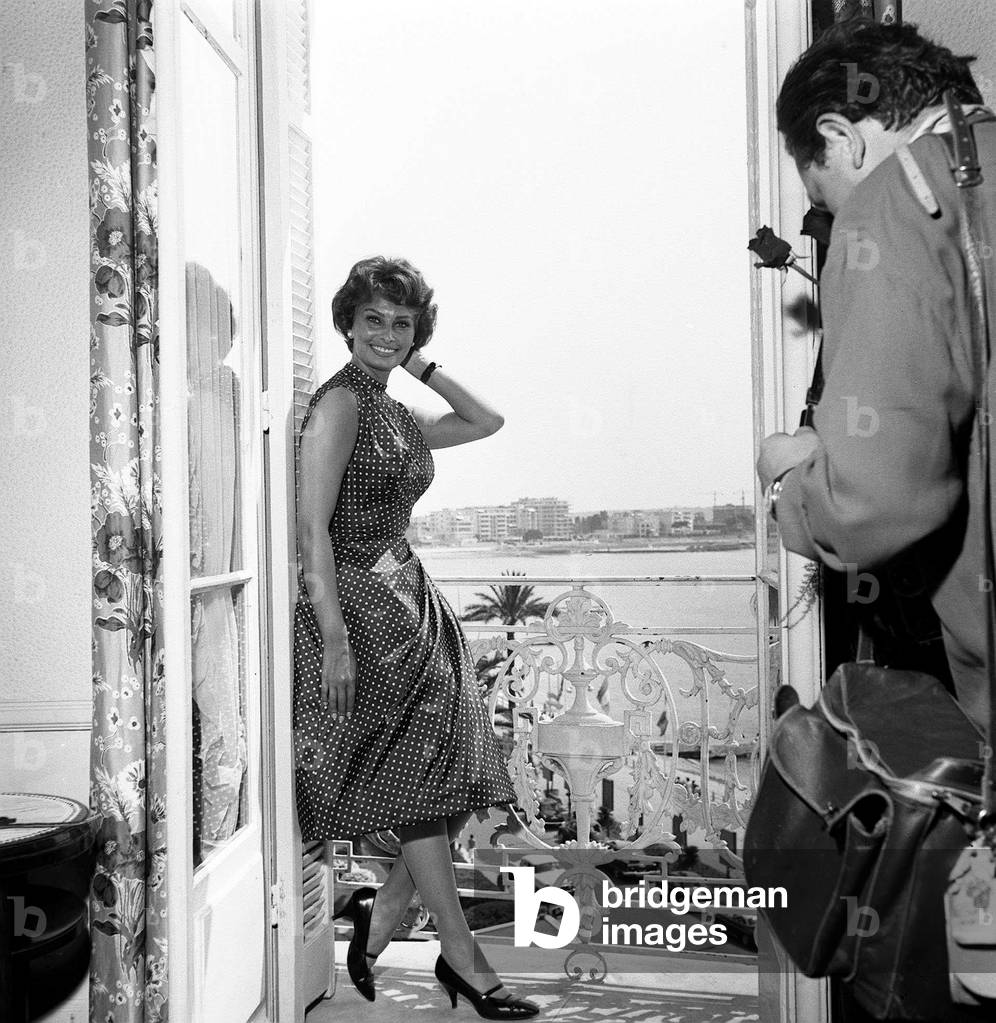 Italian actress Sophia Loren with a photographer in her hotel room at Cannes film festival, May 1958 (b/w photo)