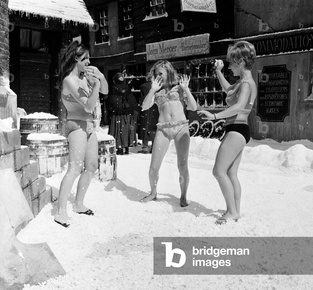 Filming of Oliver! at Shepperton studios. The scene which should have been shot in mid winter was being shot in August with a ton of featherlight polystyrene strewn about to represent the snowfall and artificial icicles hanging from ledges and pipes etc. Three young ladies, Penny Allan, Irene French, and Dinny Jones, all singers who are taking part in the film decided to get into bikini's, snowball Harry Secombe and generally frolic in the 'snow'. 3rd August 1967 (b/w photo)