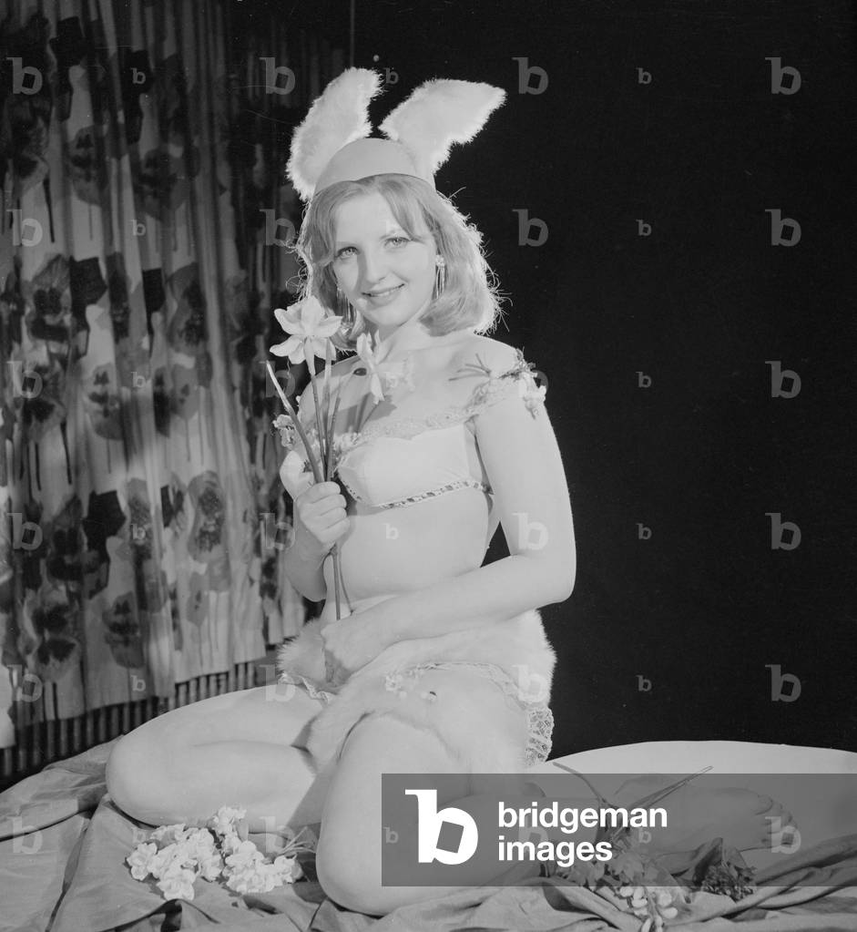 Reveille Easter Bunny Feature, Model Peggy Cage seen here wearing a fur trim bathing costume and rabbit ears, c.1960 (b/w photo)