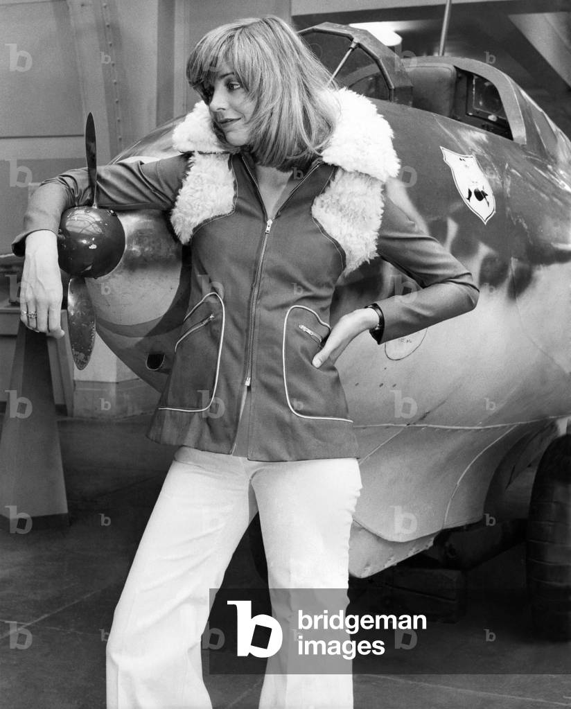 If all girl pilots wore gear like this, there would be havoc in the hangars! Wendy's snug-fitting flying jacket is in canvas with lambswool collar and lapels, has zip front and slant packets. Cream canvas flares are by Stirling Cooper September 1972