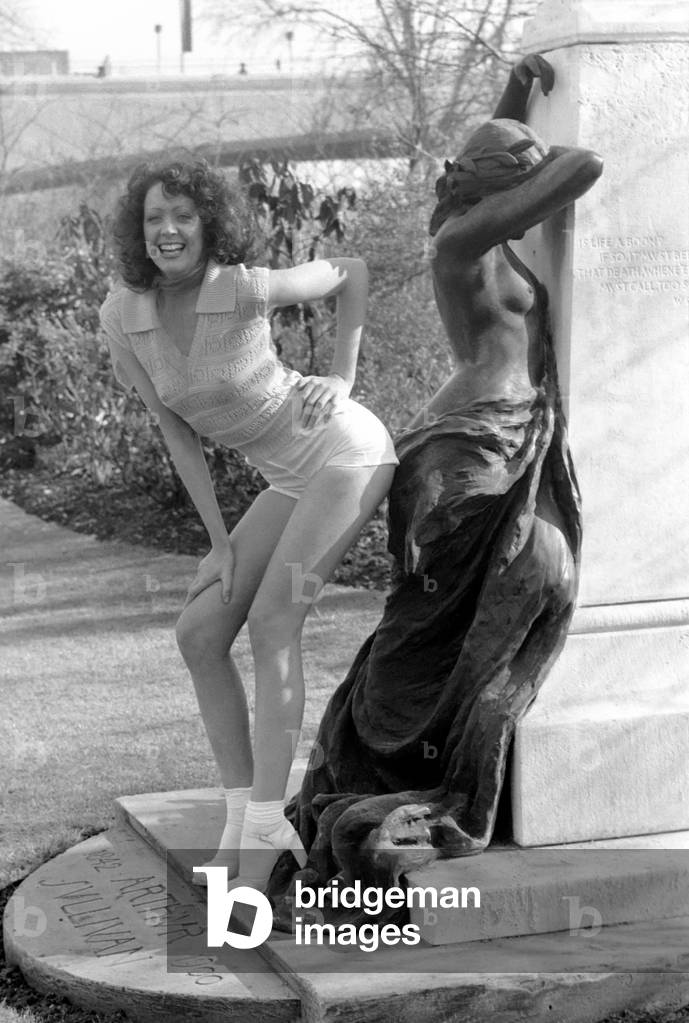Fashion scene from Woolworth's. Woman standing next to a sculpture in the park wearing short sleeved top 
February 1975