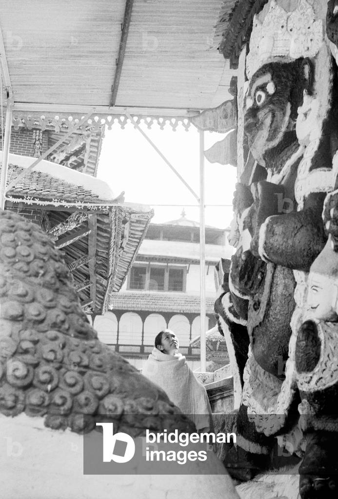 A woman seen here looking at a depiction of a Hindu god on the facade of a Hindu temple in Katmandu, Nepal, February 1961 (b/w photo)