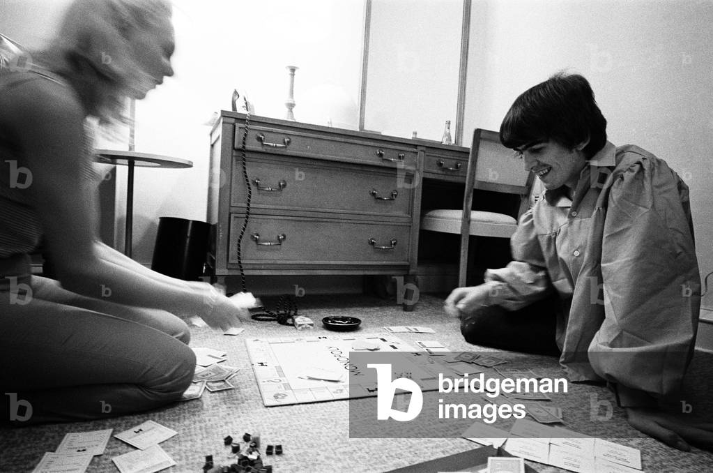George Harrison enjoys a game of Monopoly with singer songwriter Jackie de Shannon, one of the tour's support acts, at the Lafayette Motor Inn, Atlantic City, New Jersey, USA, Sunday 30th August 1964 (b/w photo)