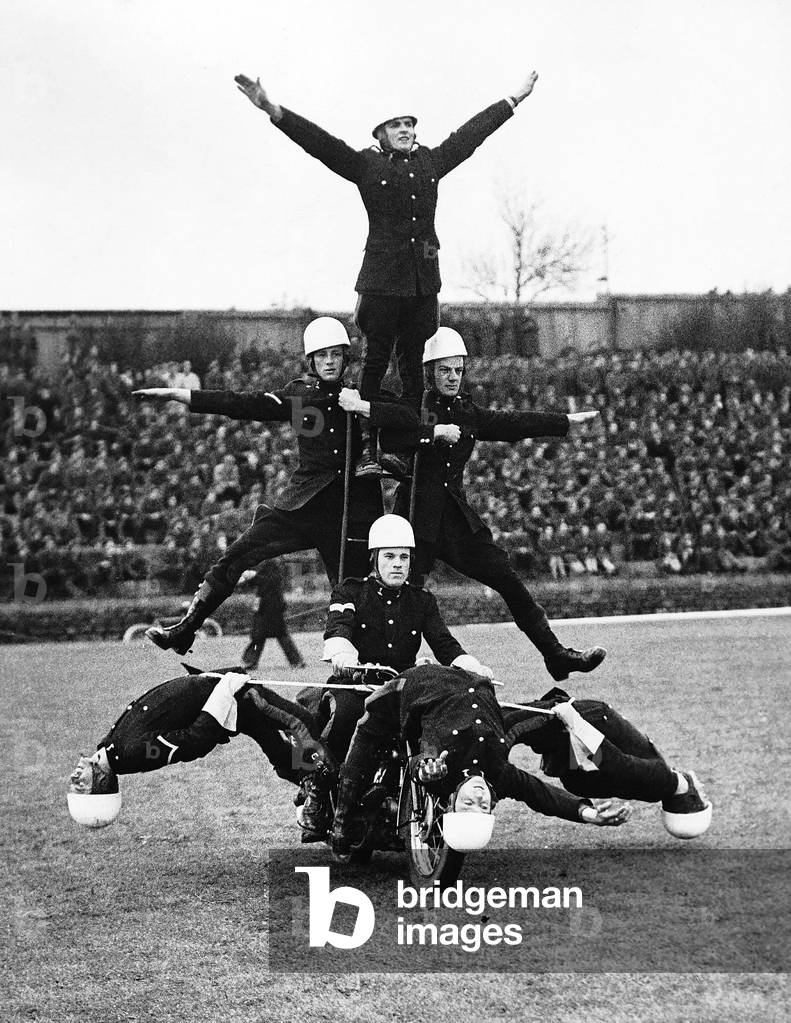 Royal Signal Corps Motor Cycles display team riding around in an arena standing and hanging off of a Motor Bike, 06/05/1948 (b/w photo)