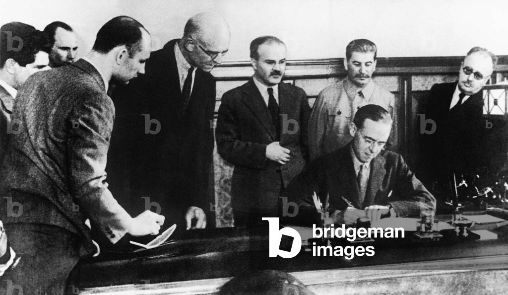 The signing of the pact of mutual assistance between the governments of USSR and Great Britain in the war against Germany. Sir Stafford-Cripps signing the document watched by l-r: Kozyrev, Russell, Potrubatch, Dunlop, Molotov, Stalin and trant. 1940s (b/w photo)