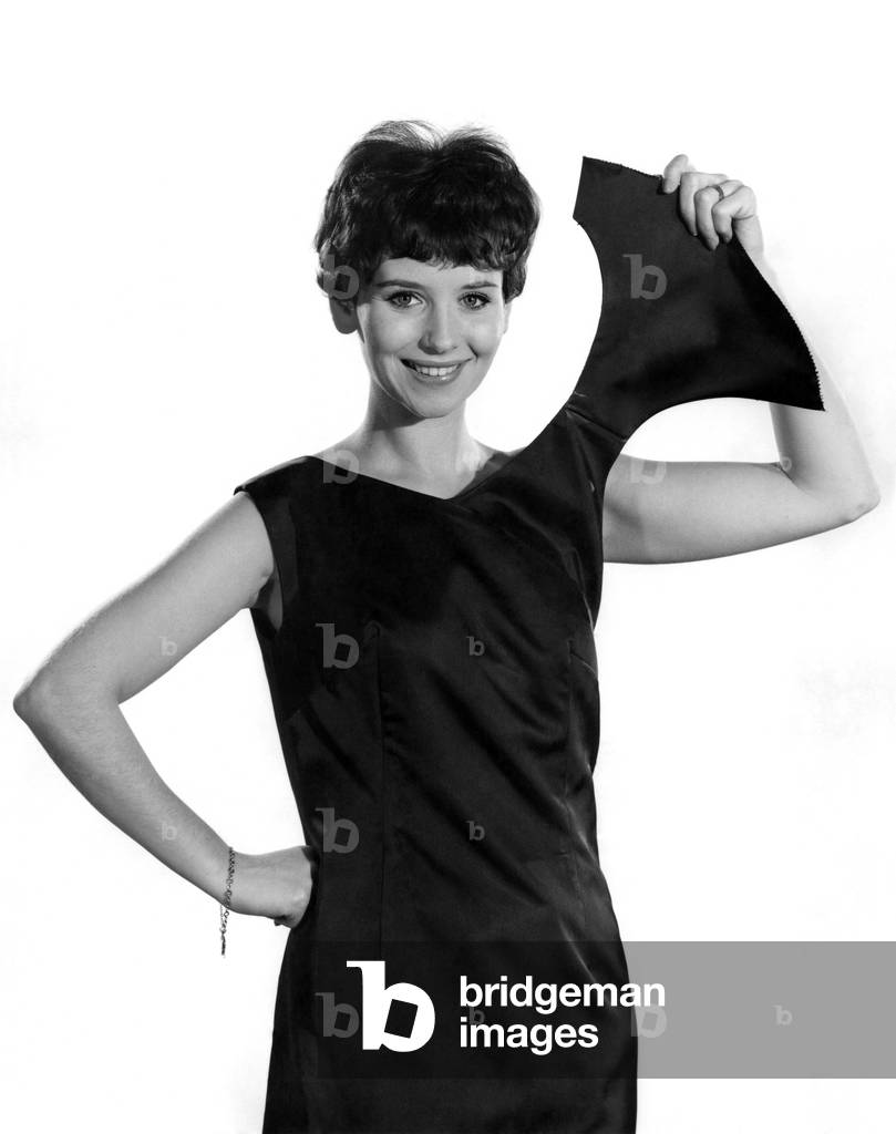 Model wearing a sleeveless black dress showing off one of the shoulder straps
January 1961
