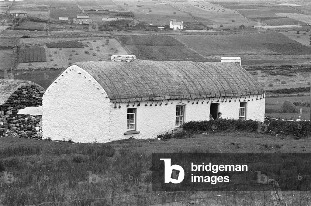 One of the traditional farmhouses with a thatched roof over looking the fields and hills of Glencolumbkille in County Donegal 7th September 1963