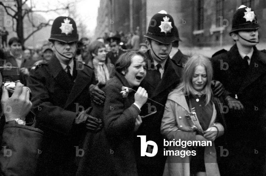 Two hysterical, weeping girls are led away from the steps of the register office by police officers - one of them clutches a flower from the bride's bouquet.March 1969