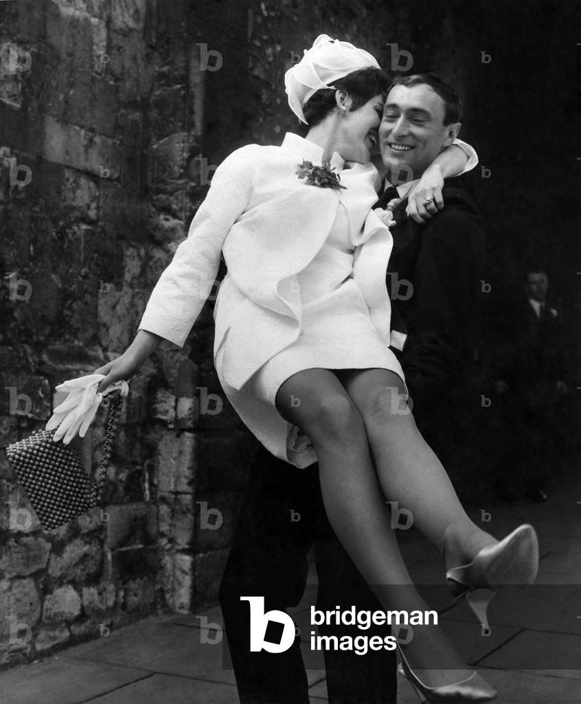 Bride carried by the groom out of the church after their wedding, March 1967 (b/w photo)