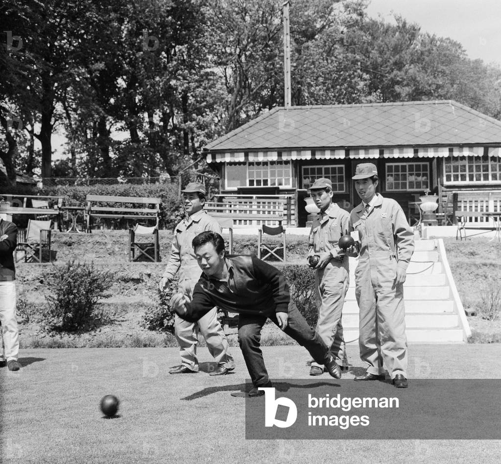 Japanese rider Shimazaki playing bowls with his team of mechanics watching. 5th June 1962 (b/w photo)