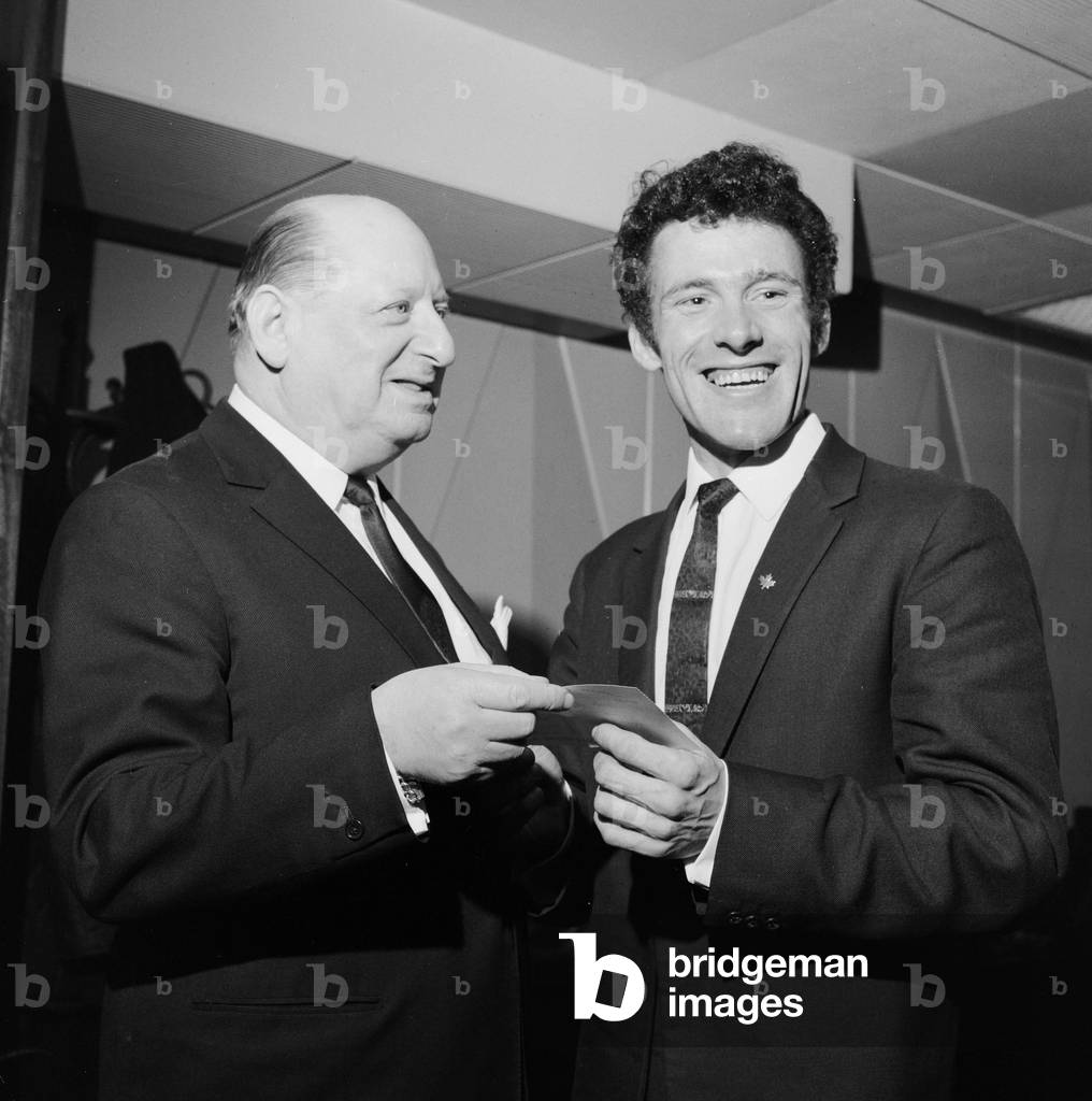 Media Mogul Lew Grade hands a cheque for £500 to 27 year old Tom Graham of Blackheath, London after his winning game score of 300, the first perfect game score in the London area at Tenpin bowling, won him the cash prize. 13th January 1969 (b/w photo)