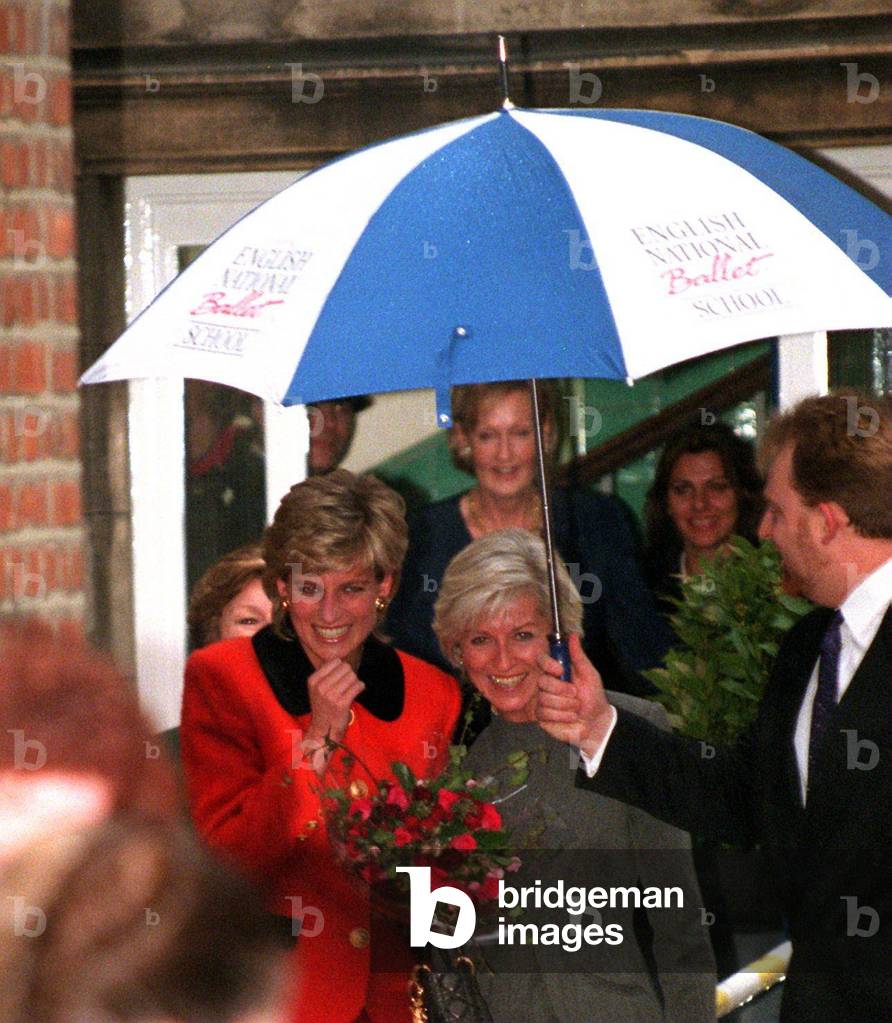 Princess Diana has fits of laughter during a visit to the English National Ballet School in Fulham due to a policeman's umbrella being blown inside out, December 1995 (photo)