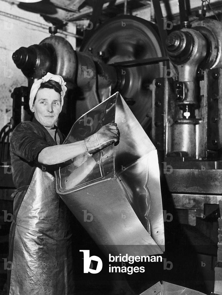 Lily Hill at her giant press stamping out the metal foundations of baby prams at a factory in Morden, Surrey, 4th December 1947 (b/w photo)