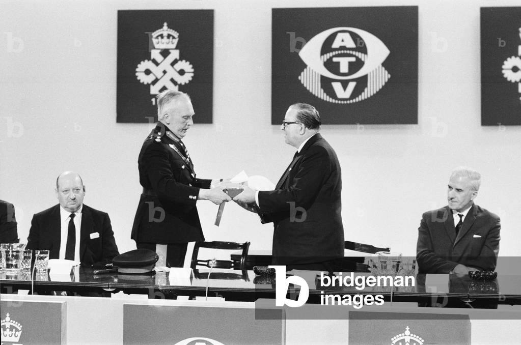 Major General Sir George Burns, Lord Lieutenant of Hertfordshire presents the Queens Award to Industry to Lord Rennick, chairman of the ATV network watched by Lew Grade (seated left) and the Postmaster General Edward Short (seated right) at the ATV Studios in Elstree. 4th July 1967 (b/w photo)