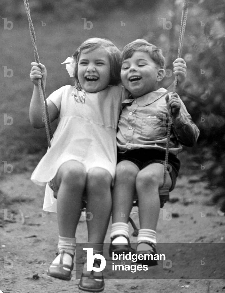 Young boy and girl playing together on the swing
Circa 1945