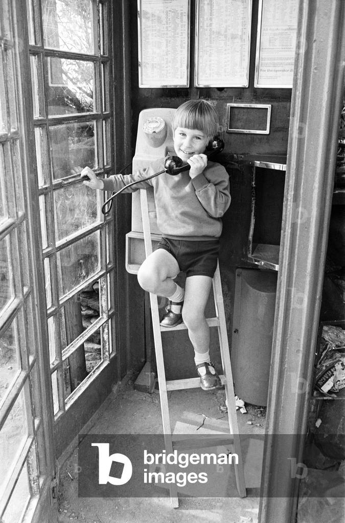 Five year old Andrew Butler, complete with a mini-stepladder, phones his girlfriend, six year old Jayne Myers from the phone box at the end of his road. 6th September 1972 (b/w photo)