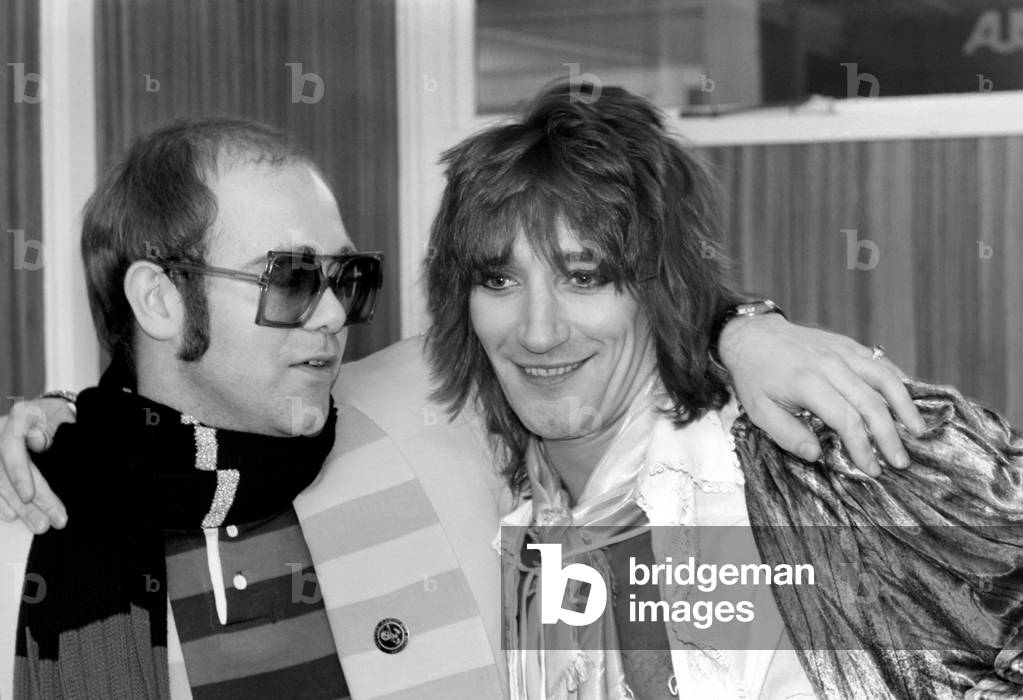 Rod Stewart and Elton John. Pop superstars Rod Stewart and Elton John make it up back stage at Olympic tonight just before Rod went on stage for the third night of his series of London concerts, December 1976 (b/w photo)