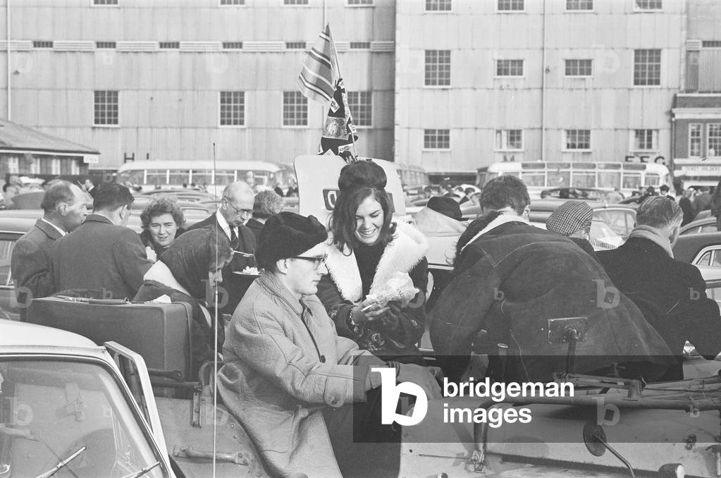 Supporters of Oxford and Cambridge Universities gather in the West Car Park at Twickenham for a traditional picnic lunch before the Varsity rugby match. 8th December 1964 (b/w photo)