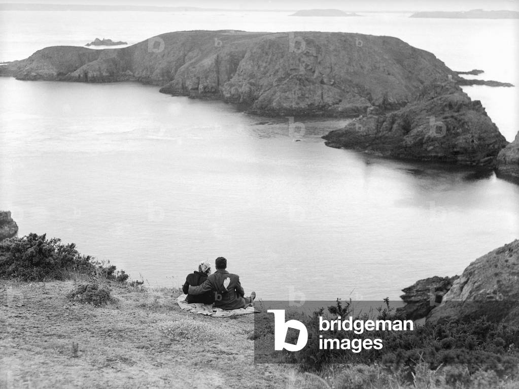 A couple enjoy some time together looking out across the sea on the Channel Island of Sark, c. 1930 (b/w photo)