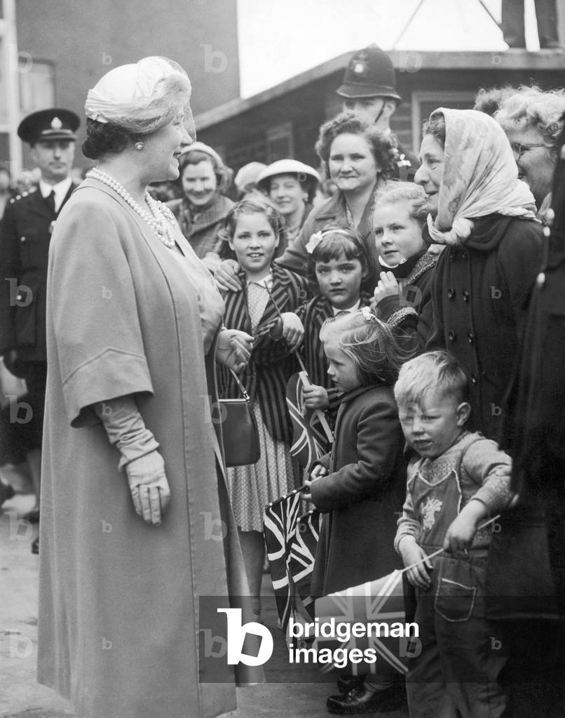 Queen Elizabeth the Queen Mother greets crowds gathered outside the Great Colmore Street Estate flats in Grant Street during her visit to Birmingham. 2nd May 1957 (b/w photo)