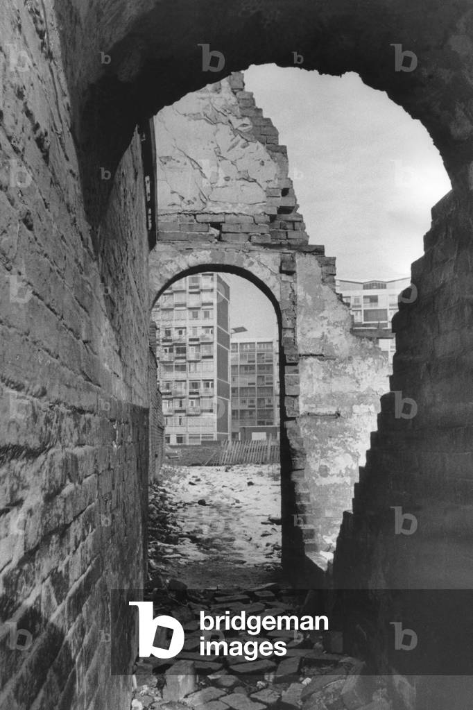 Bulldozers are clearing away the old Hillfields streets to make way for the high-rise flats. Our photograph shows some of the remaining buildings still to be demolished with the new flats looming up through the old archway. 11th February 1970 (b/w photo)