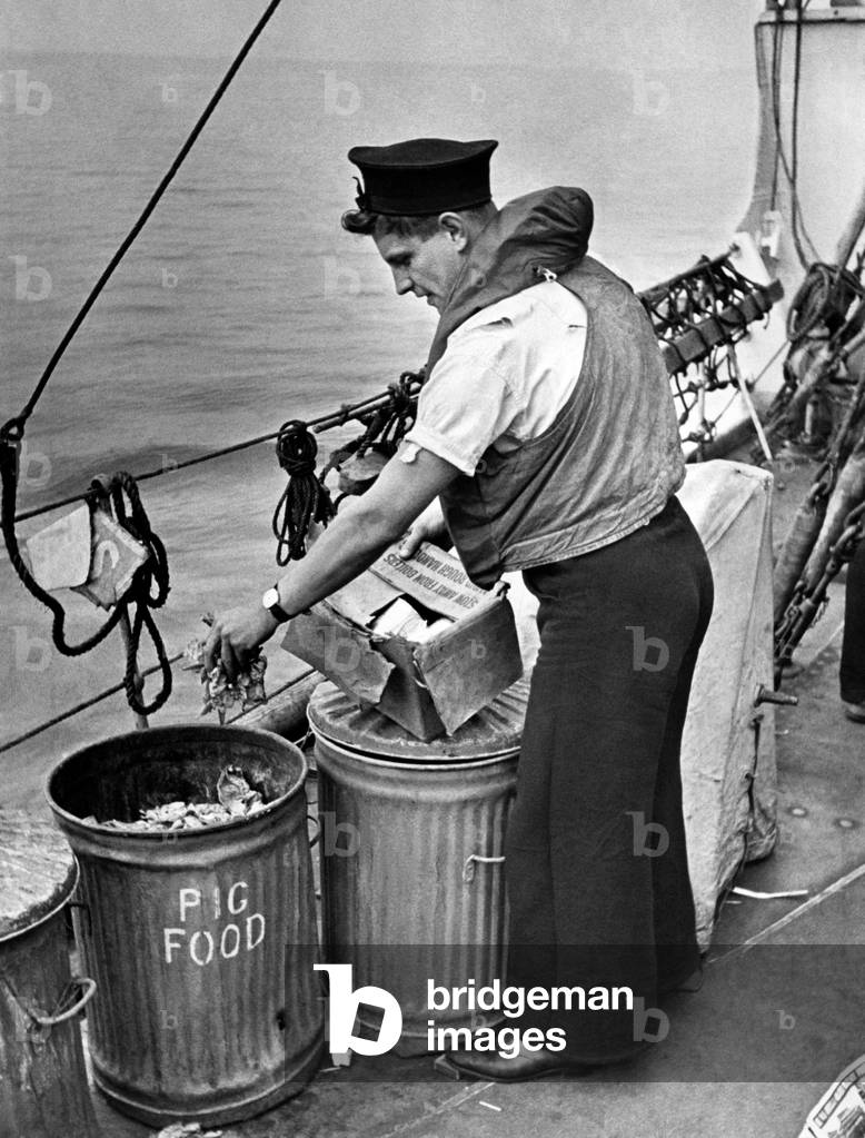 Nothing to wasted at sea. Seaman placing waste in salvage tins so familiar to land-lubbers. Scene taken on H.M.S. Destroyer whilst on escort duty of convoy off East Coast of England. August 1942