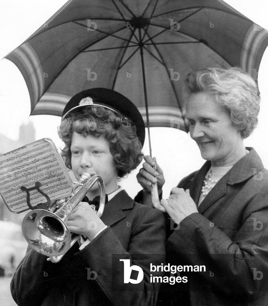 Bedlington Miners Picnic - Christine Blythe, aged 13, a cornet player from Dudley, gets protection from the rain as she does some practise, while her mother holds the umberlla, 13 June 1964