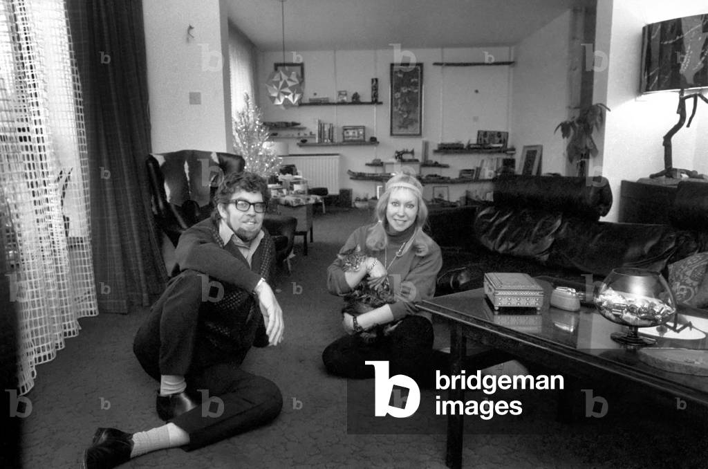 Singer Rolf Harris who lives in Sydenham, Kent, has bought the house adjoining his own modern terrace. He decided he would like to enlarge the three bedroomed house and knocked down the brick wall between the houses, himself. Rolf and his sculptress wife Alwen live their with their five year old daughter Bindi. Rolf with his wife Alwen sitting in the new house. In background is the old house. December 1969