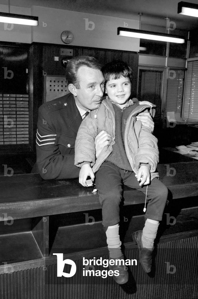 Children with policemen: A six year old boy who calls himself George Mason is photographed at the Holborn Police Station with police sgt, Frank Courtney. December 1969