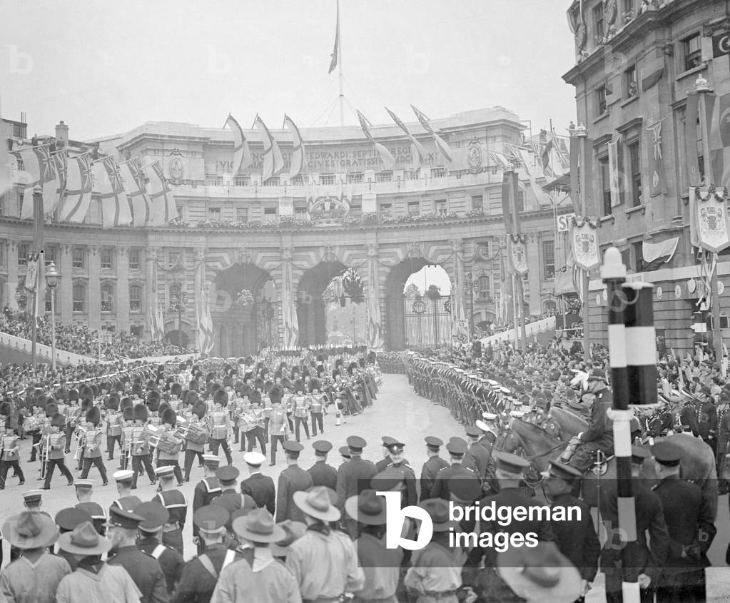 Coronation of King George VI. The procession passes through Admiralty Arch on The Mall as thousands of people watch from the side of the road. Royal Scots guards marching through accompanied by pipe players. 12th May 1937 (b/w photo)