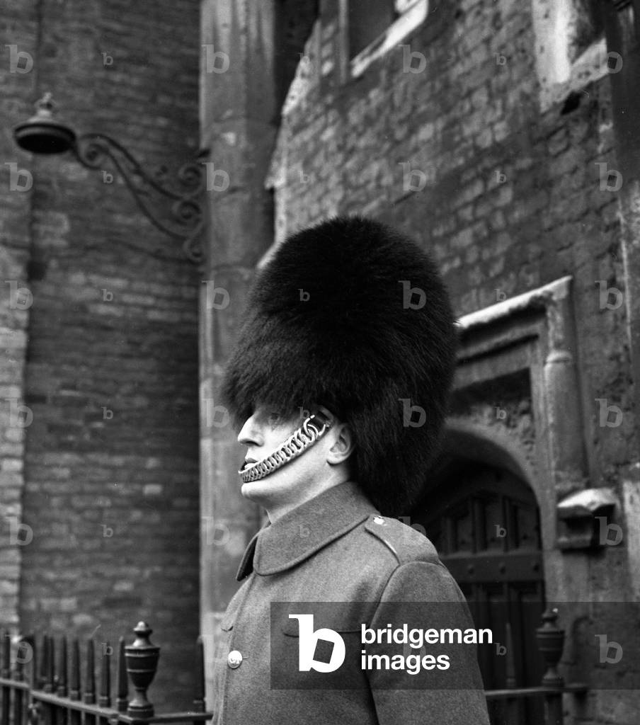 A man of the Coldstream Guards on duty outside Buckingham Palace wearing the traditional bearskin hat March 1959 (b/w photo)