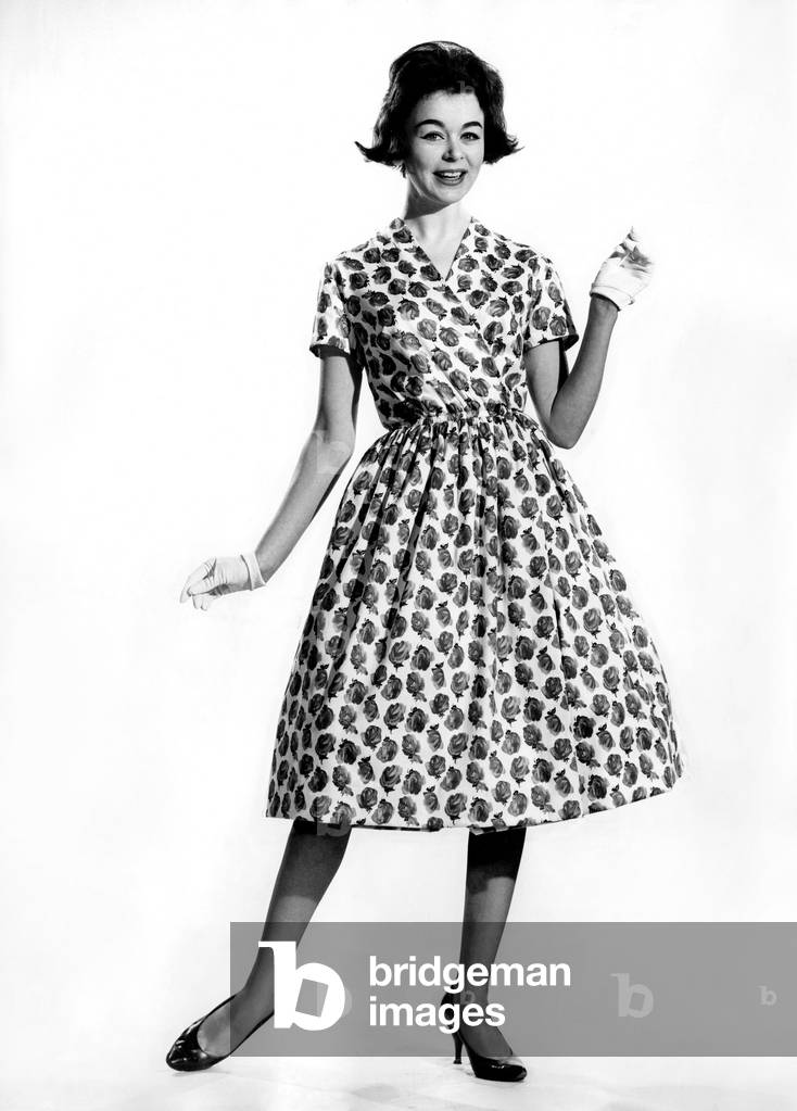 Woman wearing a patterned long dress with gloves
March 1960