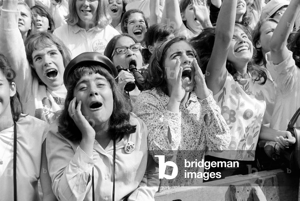 Screaming Beatles fans cheer for their idols on the streets of New York City, USA as the British pop group arrive for their American tour. 
August 1964