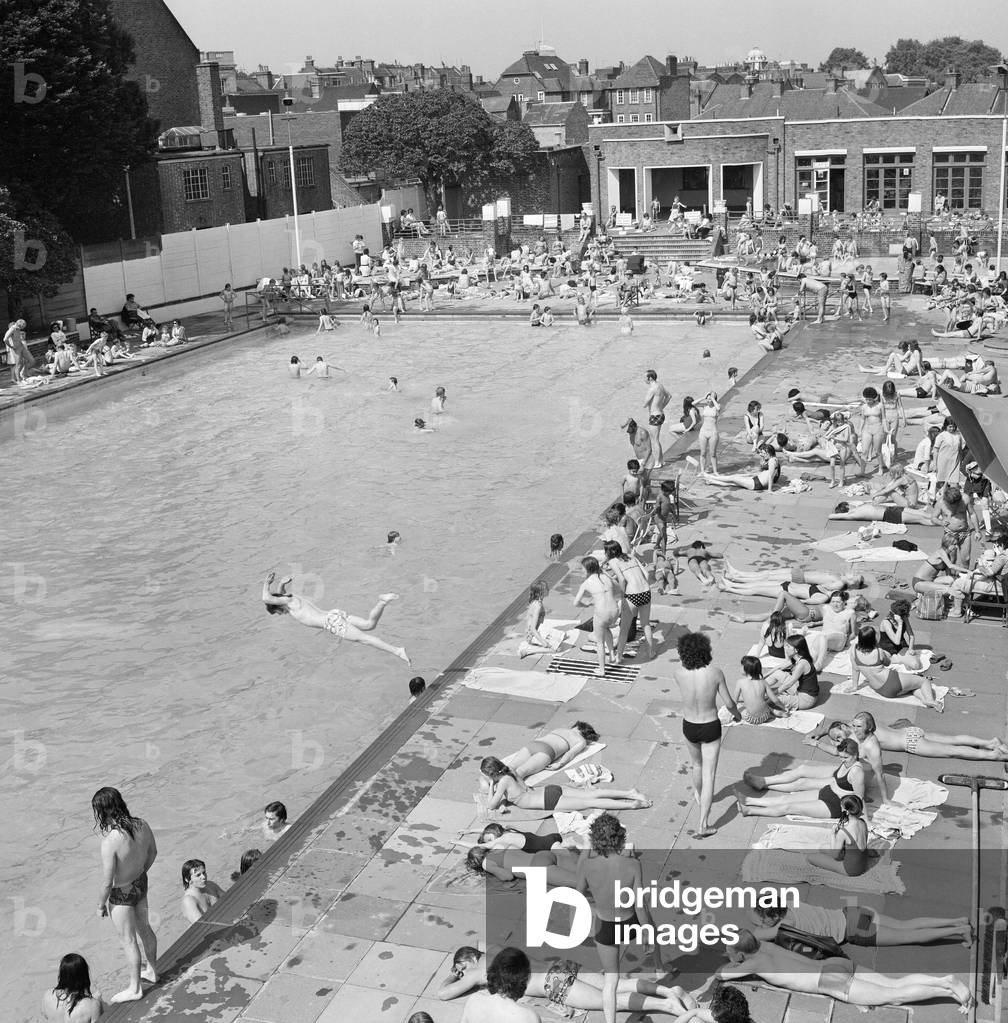 Crowds of sunbathers at the Twickenham outdoor swimming pool, London. 7th June 1975 (b/w photo)