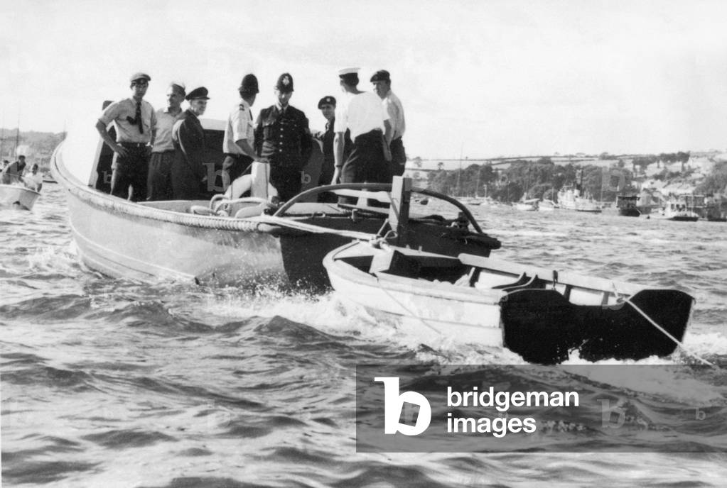 RAF rescue officers, coastguard officers and police officers tow ashore the dinghy belonging to the Darlwyne pleasure cruiser which went missing along the Cornish coast with 31 people on board. The 45 foot long boat sailed from Mylor near Falmouth and was last seen of Fowey heading home. August 1966 (b/w photo)