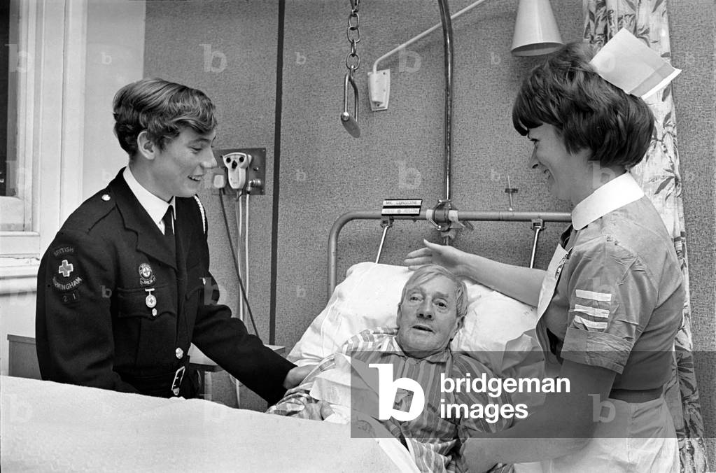 Volunteer Labour in Hospitals. 15 year old Robert Newport helping the Nurse in charge of Ward 3 at East Birmingham Hospital 
Nurse Margaret Flaherty to attend the needs of patient Mr. David Austin. 
December 1969